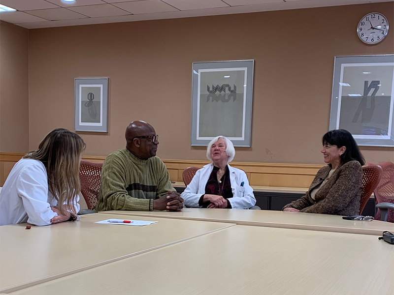 Dr. Bertagnolli and two other doctors sit together at a table with a patient